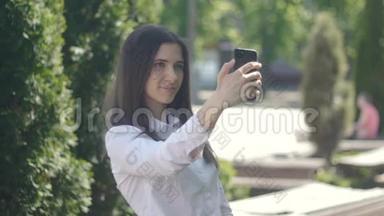 年轻女子白天在户外用智能手机拍照。 那个女孩在下午做了一个自我介绍